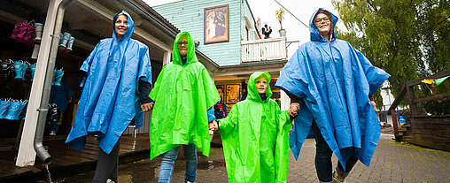 Die Familie läuft mit blauen und grünen Regenponchos durch die Westernstadt.