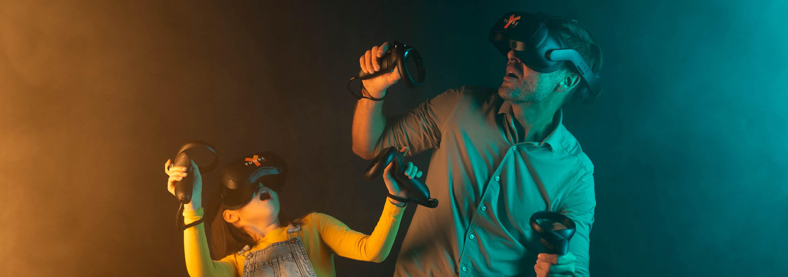 Vater und Tochter spielen mit VR-Brille und Handsteuerungen spielen gemeinsam ein digitales Spiel im FORT VentuRe.