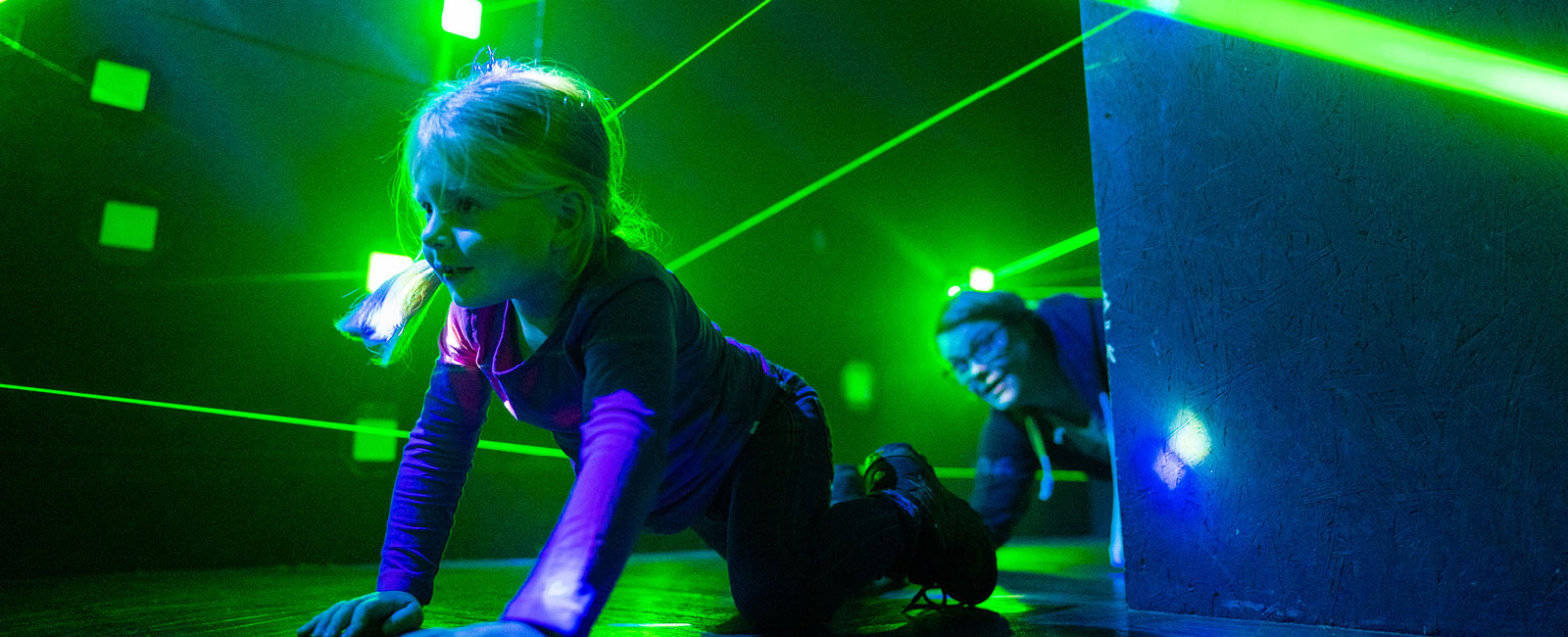 Das Mädchen krabbelt im Laserlabyrinth durch den FunnyFuxBau LaserParcours.