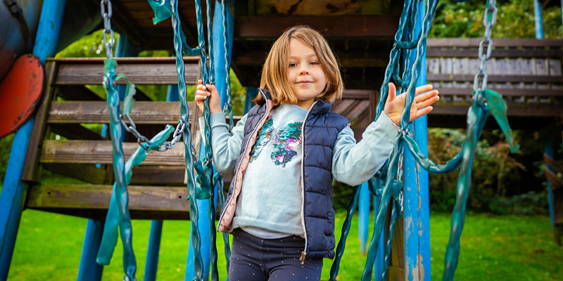 Das kleine Mädchen balanciert auf den Spielgeräten im Freizeitpark.