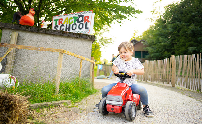 Der kleine Junge auf dem Rutschauto rast um die Kurven in der Tractor School.