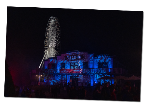 In der Dunkelheit sehen das Riesenrad und der Saloon mit Beleuchtung beeindruckend aus