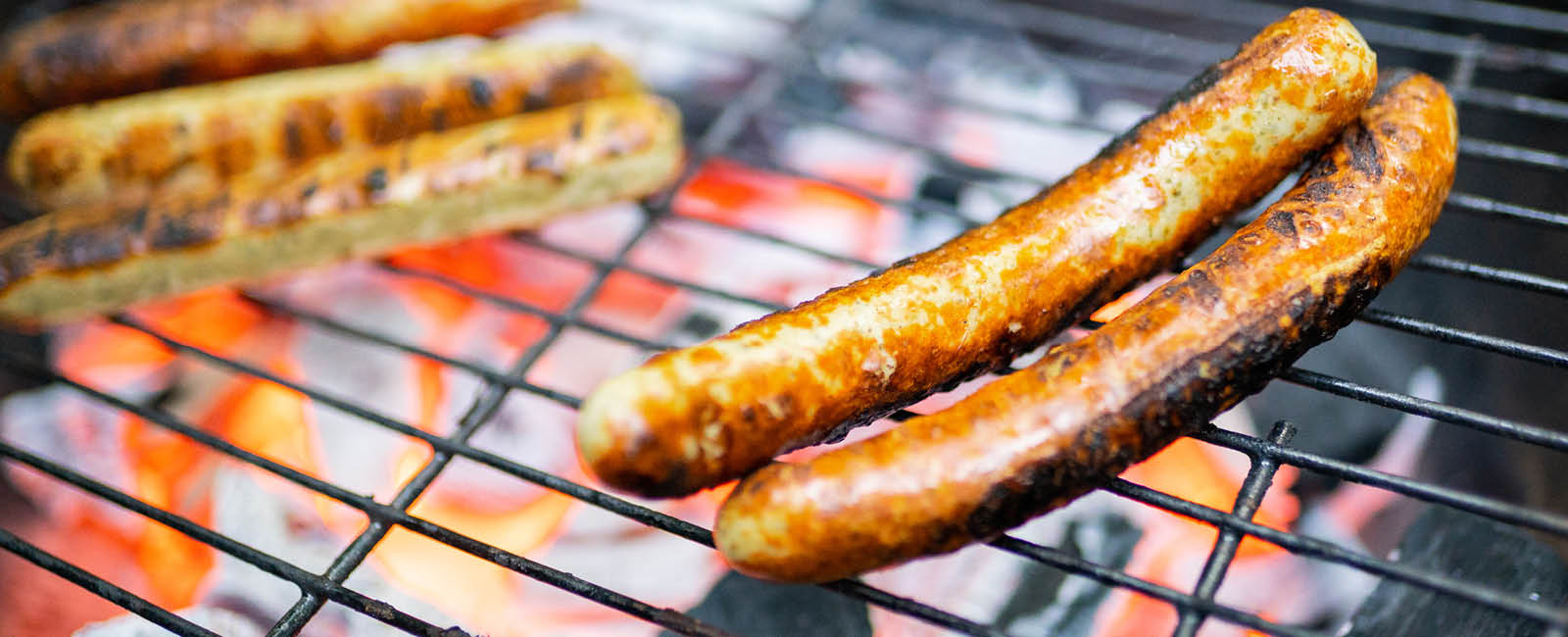 Die Würstchen bruzeln auf dem Grill und es sieht sehr lecker aus.