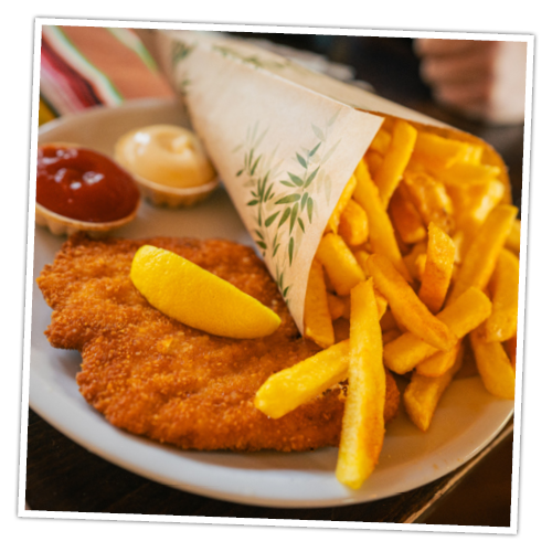 Ein Schnitzel nach Wiener Art mit Pommes, Majo und Ketchup im Restaurant in der Westernstadt.