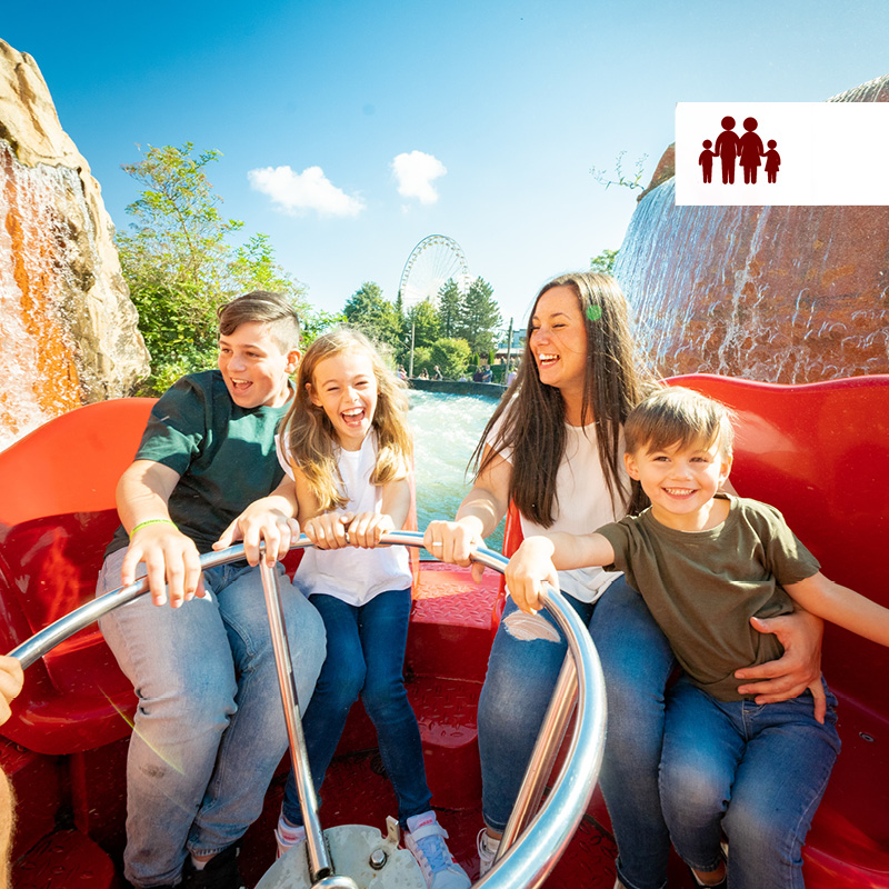 Familie im roten Boot der Attraktion Los Rapidos mit Riesenrad im Hintergrund