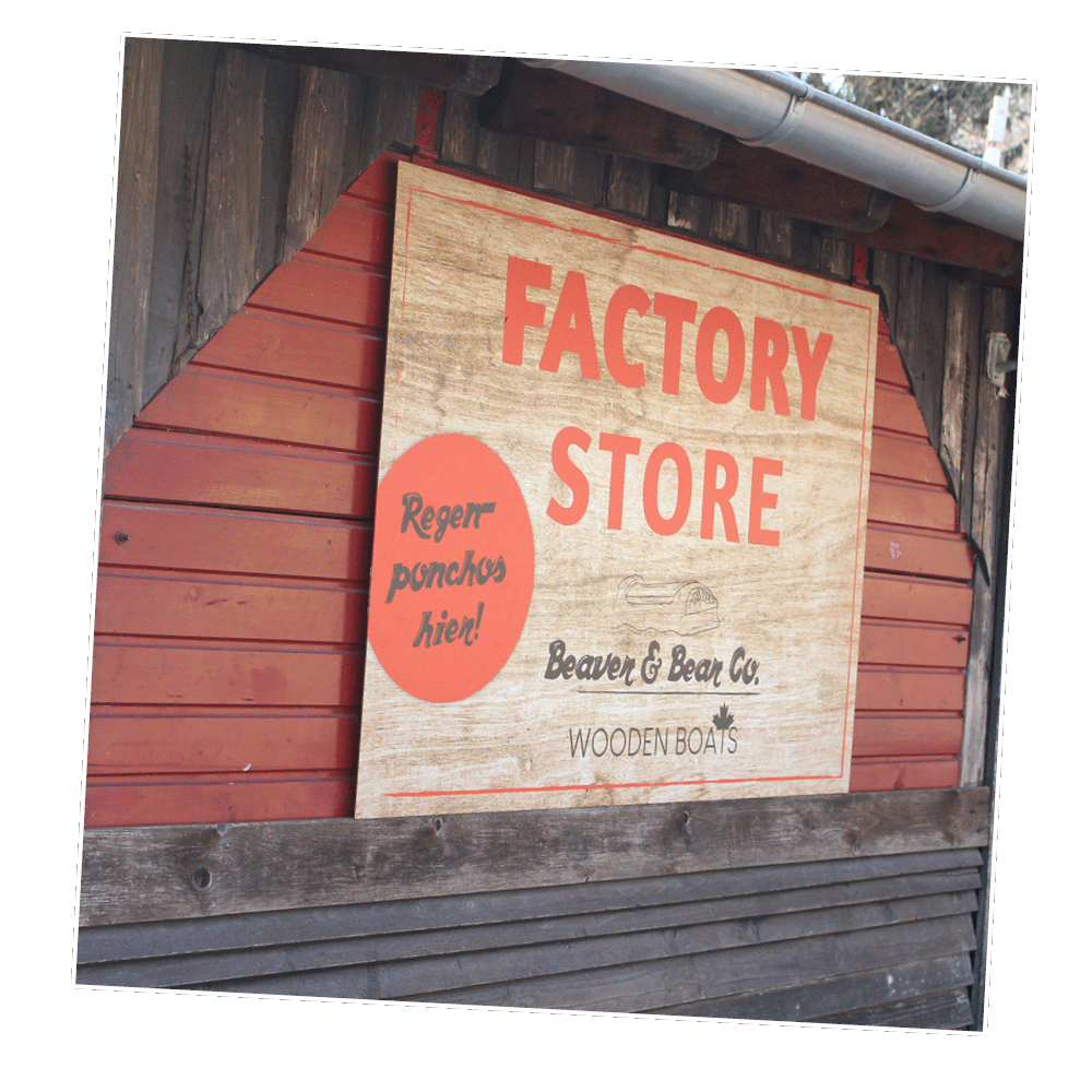 Das Factory Store Schild hängt vor der braunen Holzwand.