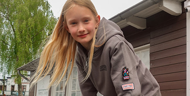 Das Mädchen trägt eine coole Jacke mit Patches.