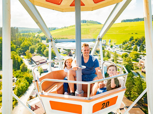 Die Gondel im Riesenrad lädt zum Verweilen ein und der Papa genießt die Aussicht mit seinen beiden Kindern.